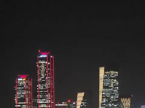 Lit office towers in Yeouido at night seen across the river